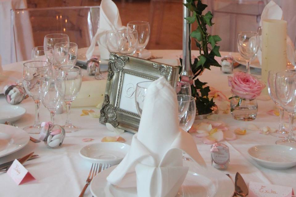 Una mesa de boda con rosas y cubertería de plata